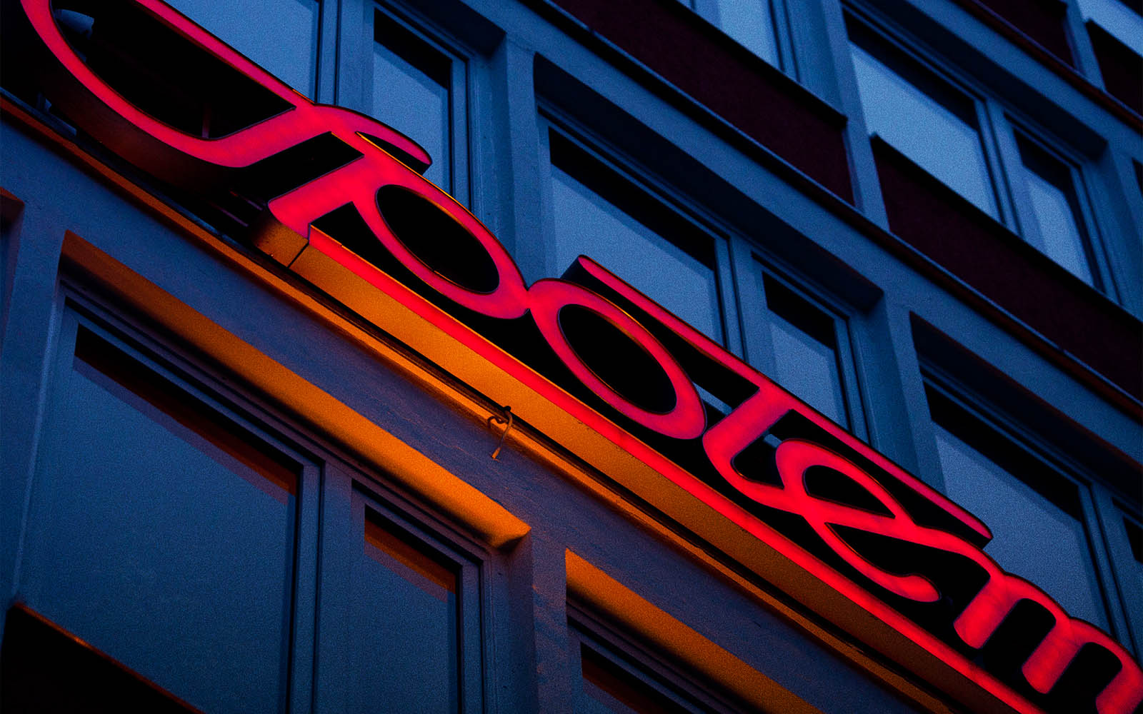 Zdjęcie przedstawia symbol typograficzny Społem w kolorze czerwonym. Jest to element elewacji jednego ze sklepów.